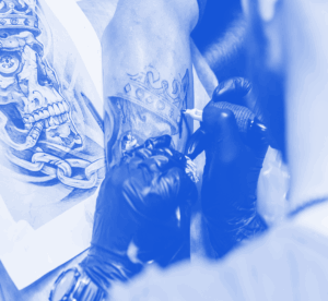 Tatuador trabajando una línea larga en el antebrazo de un cliente, con la piel estirada a dos manos