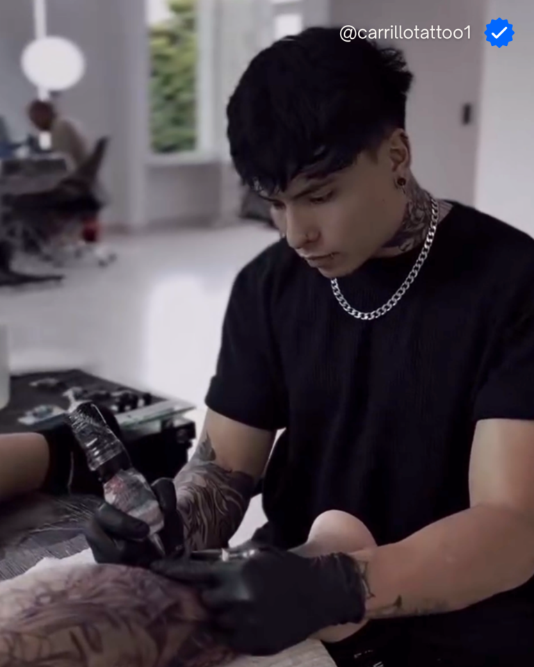 Tatuador profesional trabajando con máquina y guantes en un estudio